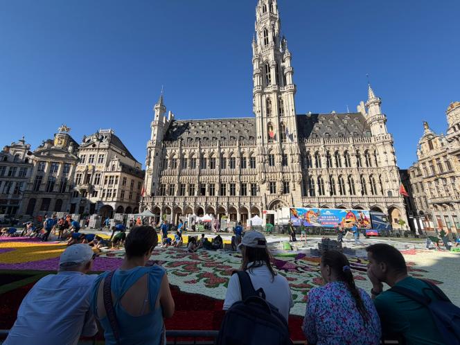Touristes observant la pose du tapis de fleurs sur la Grand-Place de Bruxelles.