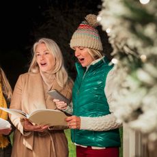 Trois femmes en train de chanter des chants de Noël.