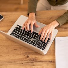 Une femme tape quelque chose sur le clavier de son ordinateur portable.
