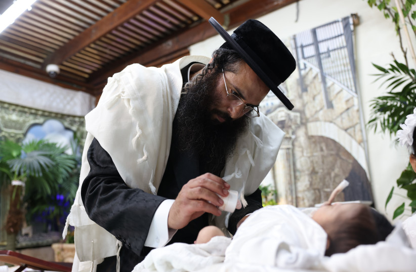 A mohel performs a circumcision ceremony to his newborn son in Northern Israel.
