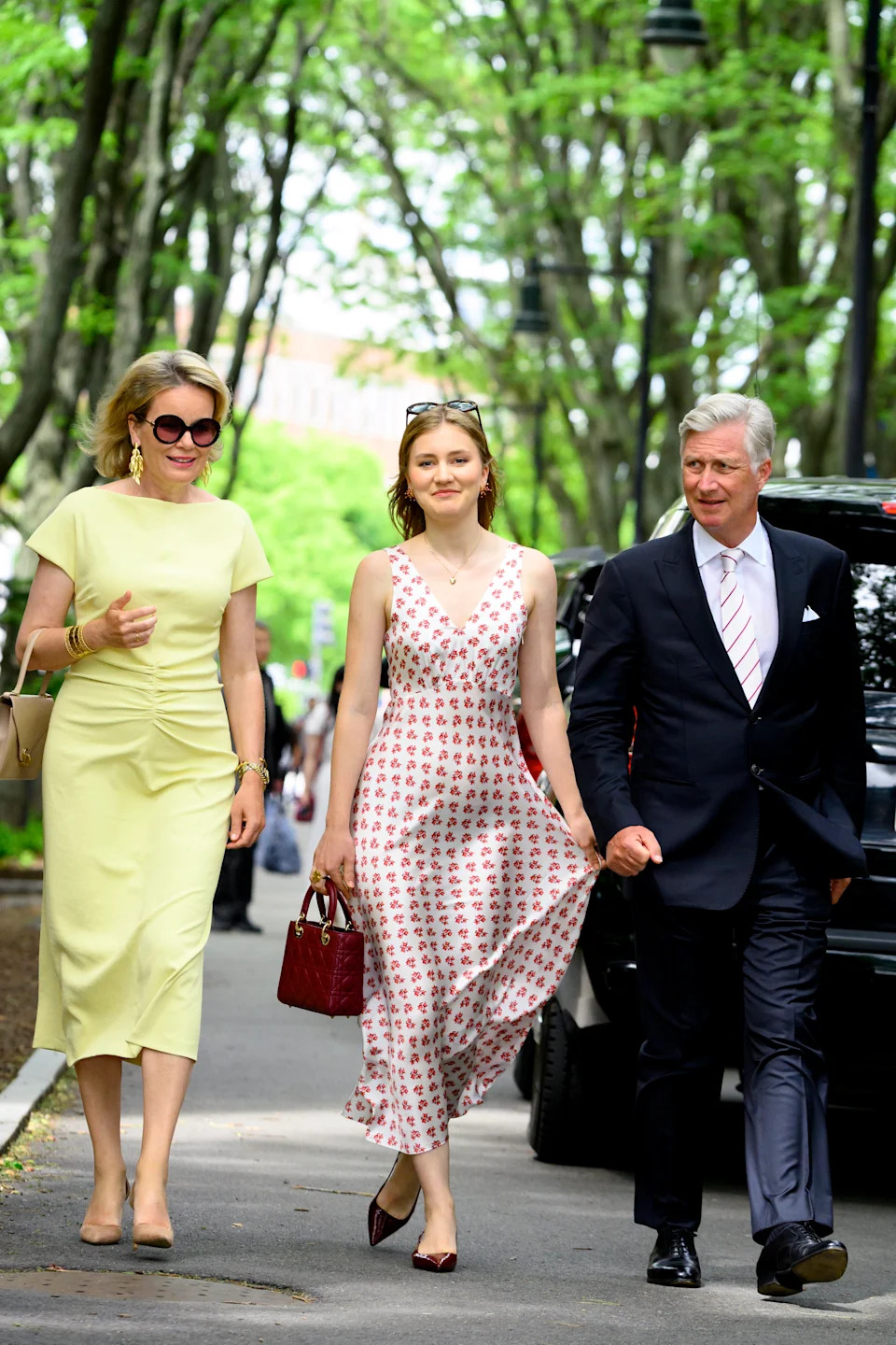 Queen Mathilde, Princess Elisabeth and King Philippe walking down a road