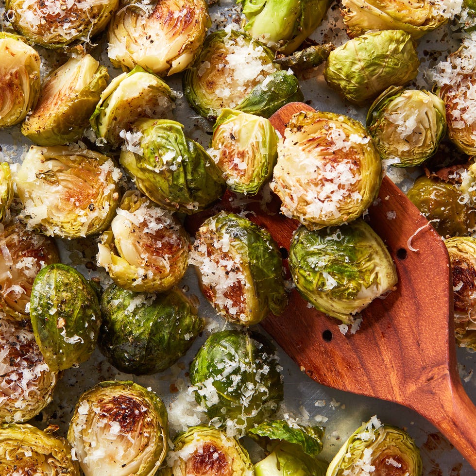 Roasted Brussels sprouts sprinkled with grated cheese on a baking tray. Roasted Brussels sprouts sprinkled with grated cheese on a baking tray.