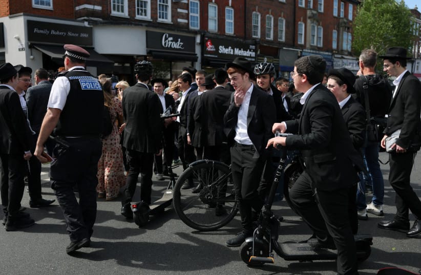 A police officer walks next to locals, after a man was arrested following a stabbing incident in the Golders Green area, which is home to a large Jewish population, in London, Britain, April 29, 2026.