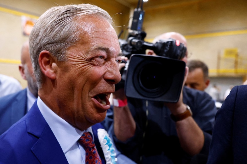 A man smiling, with a video camera also visible in the background