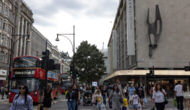 Bustling Oxford Street with shoppers, iconic red buses, and storefronts under a clear sky in a vibrant urban scene