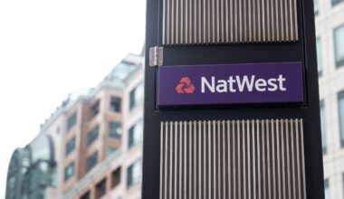 NatWest sign on a dark pillar with vertical slats, set against a blurred background of a modern office building