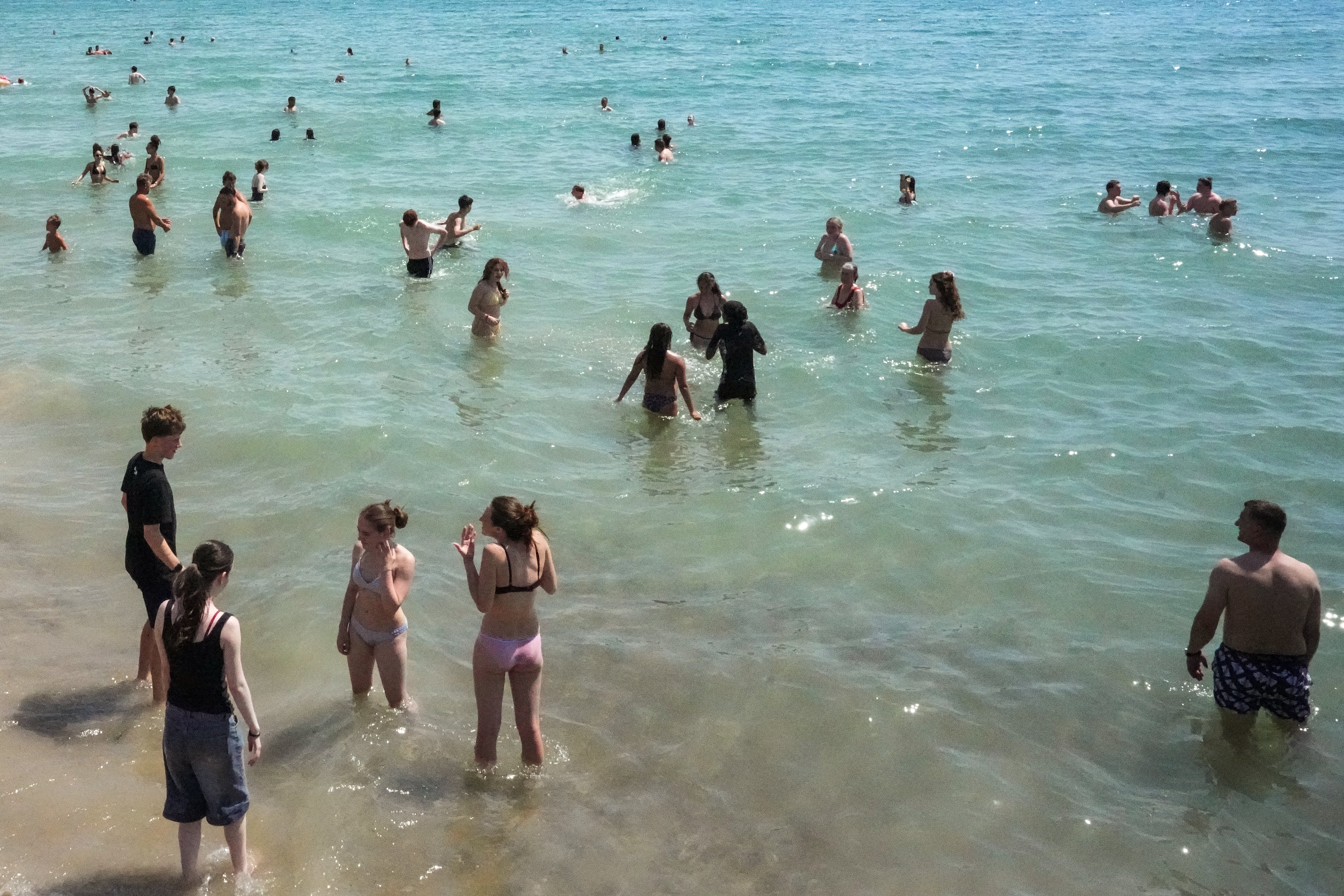 People enjoy the weather in the sea and on in the beach in Brighton, on the south coast of England