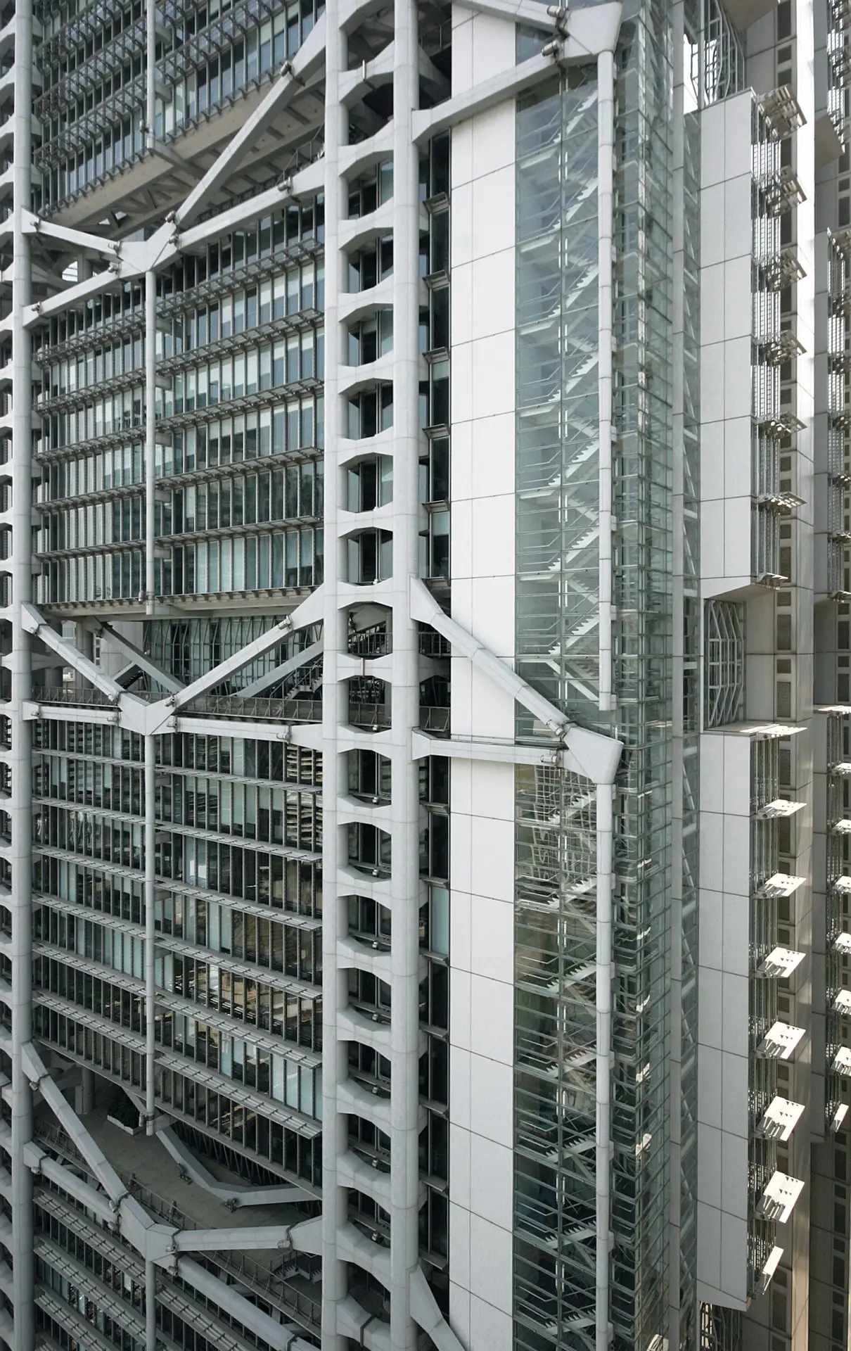 A modern high-rise façade shows steel cross-bracing, glass stair towers and dense rows of office windows.