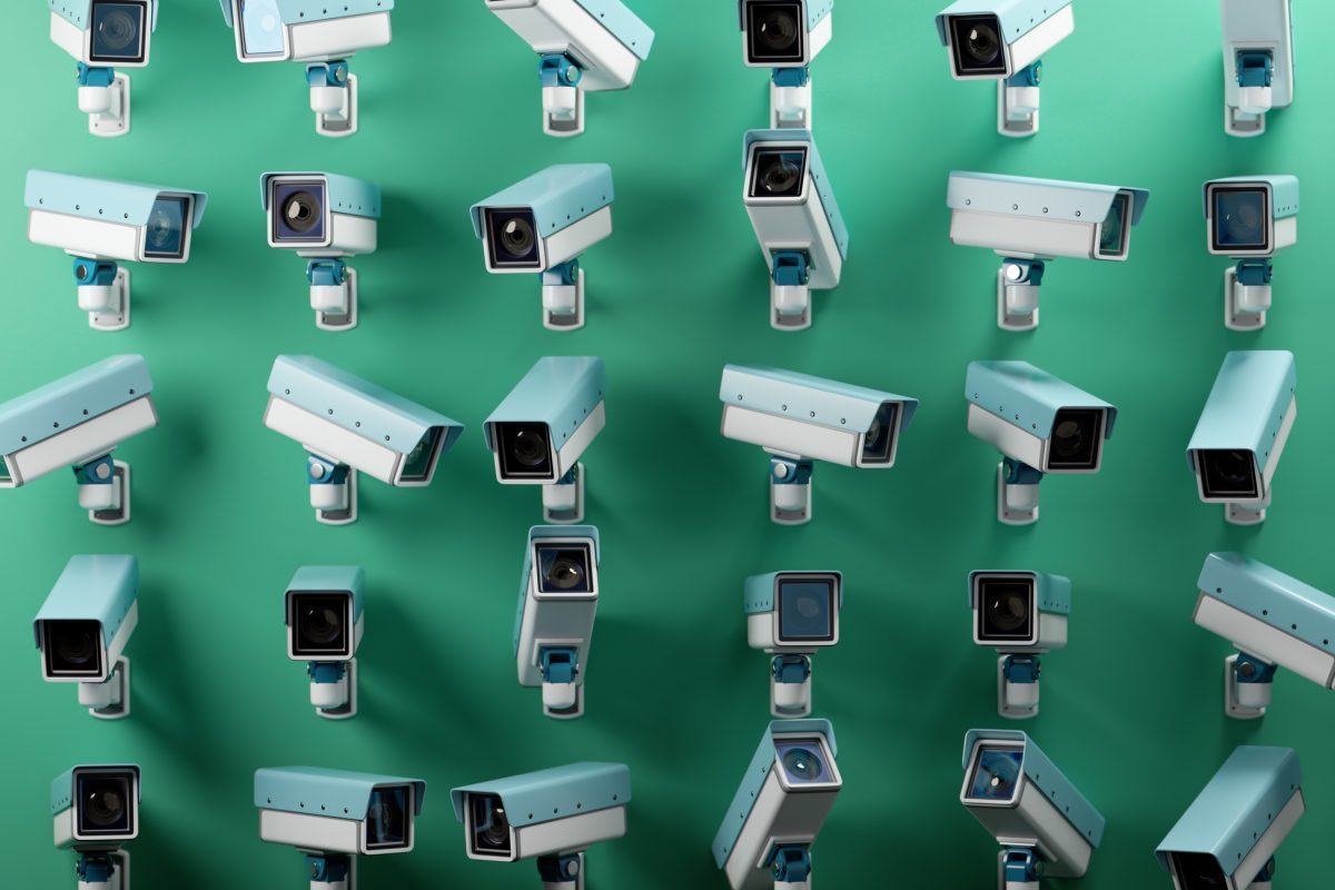 Multiple CCTV security cameras in light blue and white against a green background, emphasizing surveillance and monitoring.