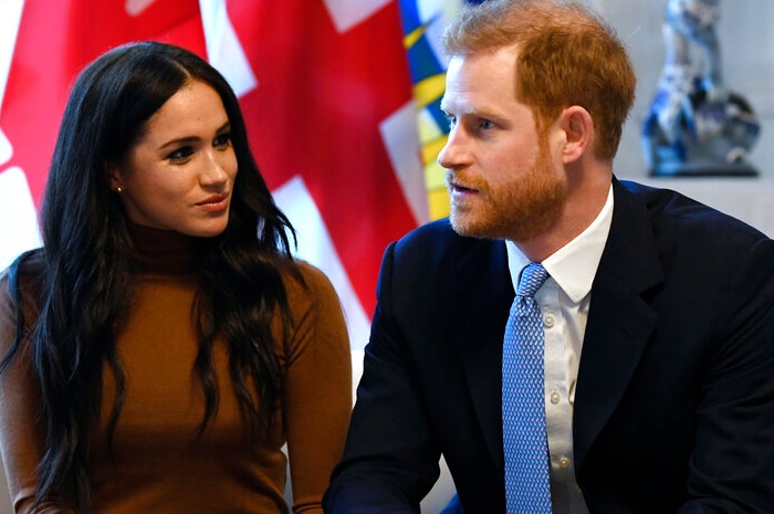 Harry and Meghan sit on a couch.