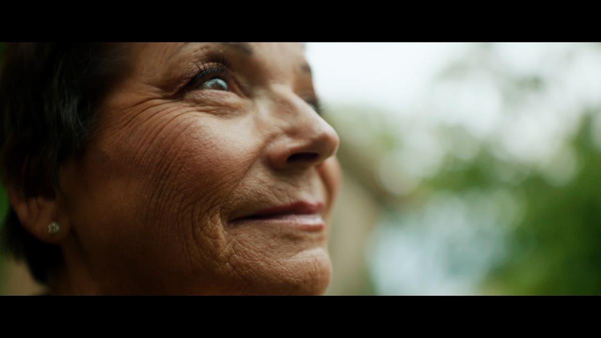 A close-up screenshot of Deb Proctor smiling away from the camera.