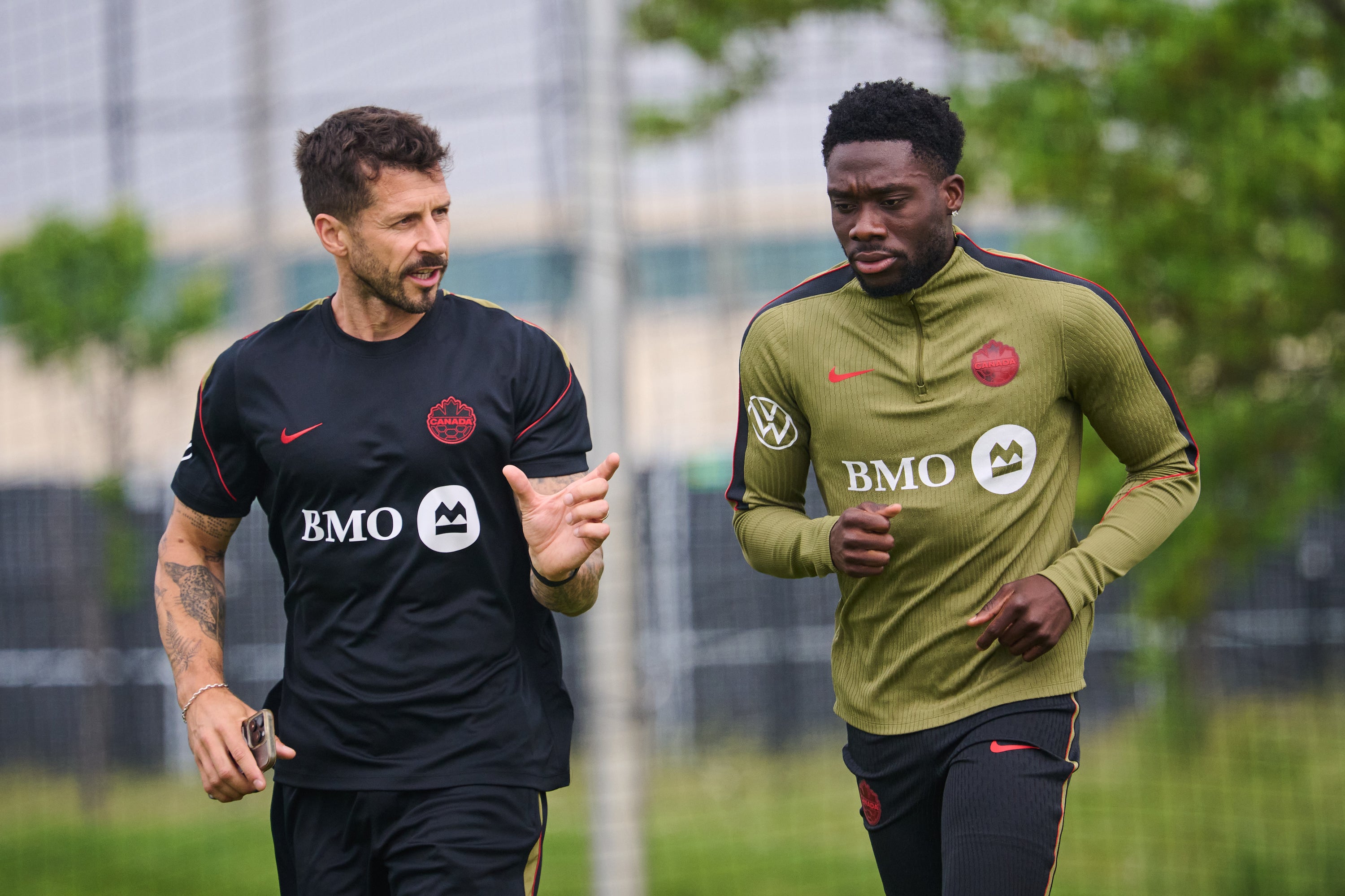 Canada's Alphonso Davies, right, runs laps during a World Cup soccer training session in Toronto
