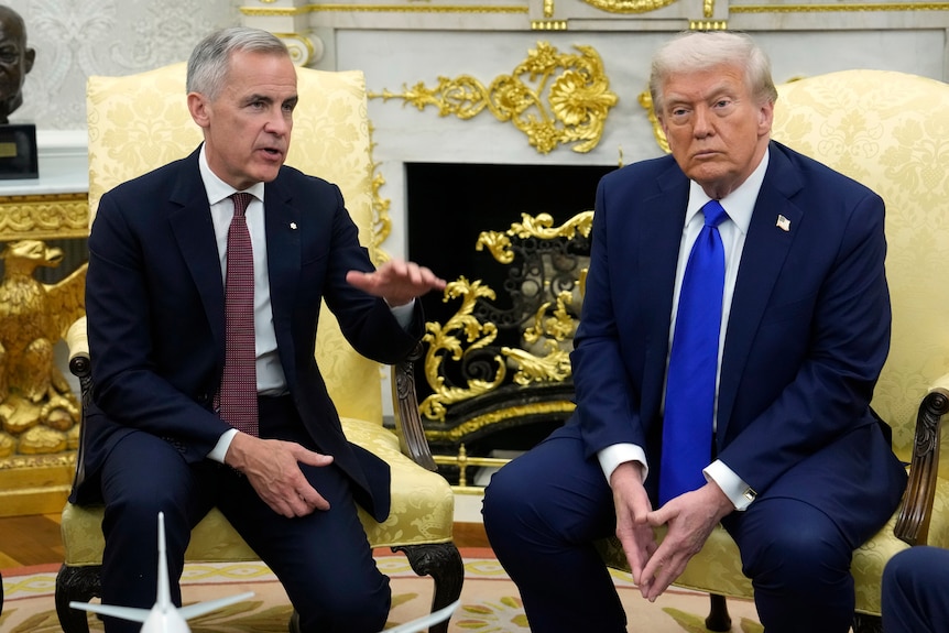 Mark Carney, left, and Donald Trump sit in armchairs in front of an ornate fire place.