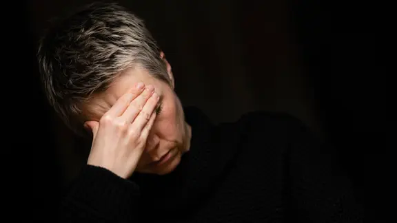 Eine Frau sitzt hält sich die Hände vor das Gesicht. | picture alliance / photothek, Thomas Trutschel Eine Frau sitzt hält sich die Hände vor das Gesicht.