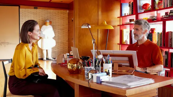 Eine Frau sitzt einem Mann am Schreibtisch gegenüber (Szene aus dem Film "Bitteres Fest") | StudioCanal/dpa Eine Frau sitzt einem Mann am Schreibtisch gegenüber (Szene aus dem Film "Bitteres Fest")