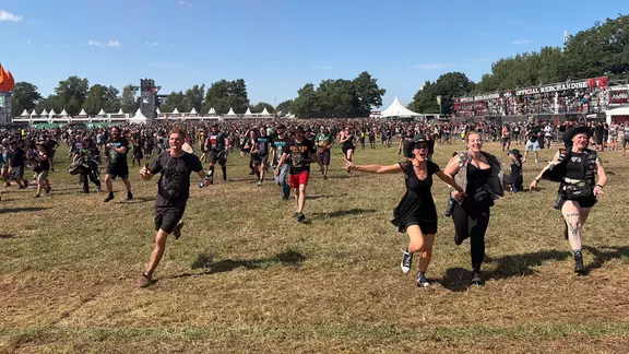 Ohne Matsch läuft es sich doch gleich viel besser auf das Wacken-Infield. | NDR, Dominik Duehrsen Fans stürmen auf den "Holy Ground" beim Wacken Open Air