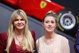 Zwei Frauen stehen nebeneinander vor einem roten Rennwagen.