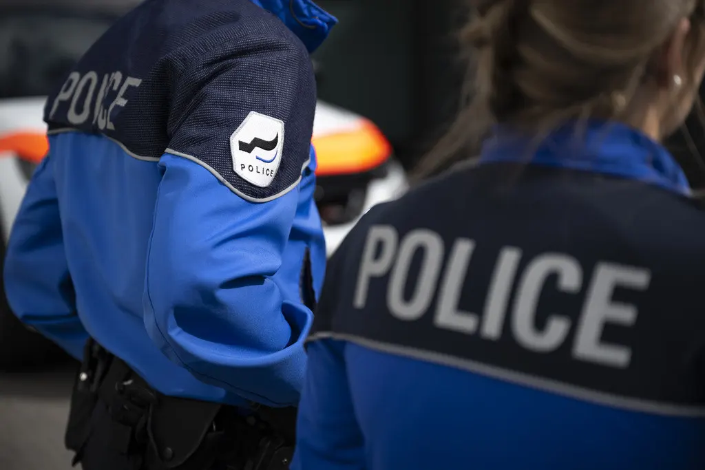 Deux agents de police en uniforme bleu avec l’inscription ’POLICE’ dans le dos, lors d’une intervention en Suisse.