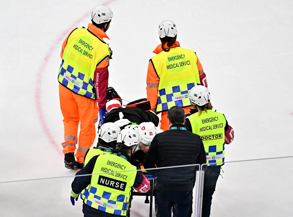 Kevin Fiala of Switzerland is taken off the ice by medical staff on a stretcher after sustaining an injury against Canada in men's ice hockey group.
