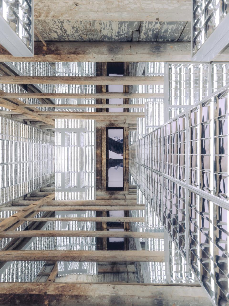 Interior view of a structure featuring reflective surfaces and wooden beams.