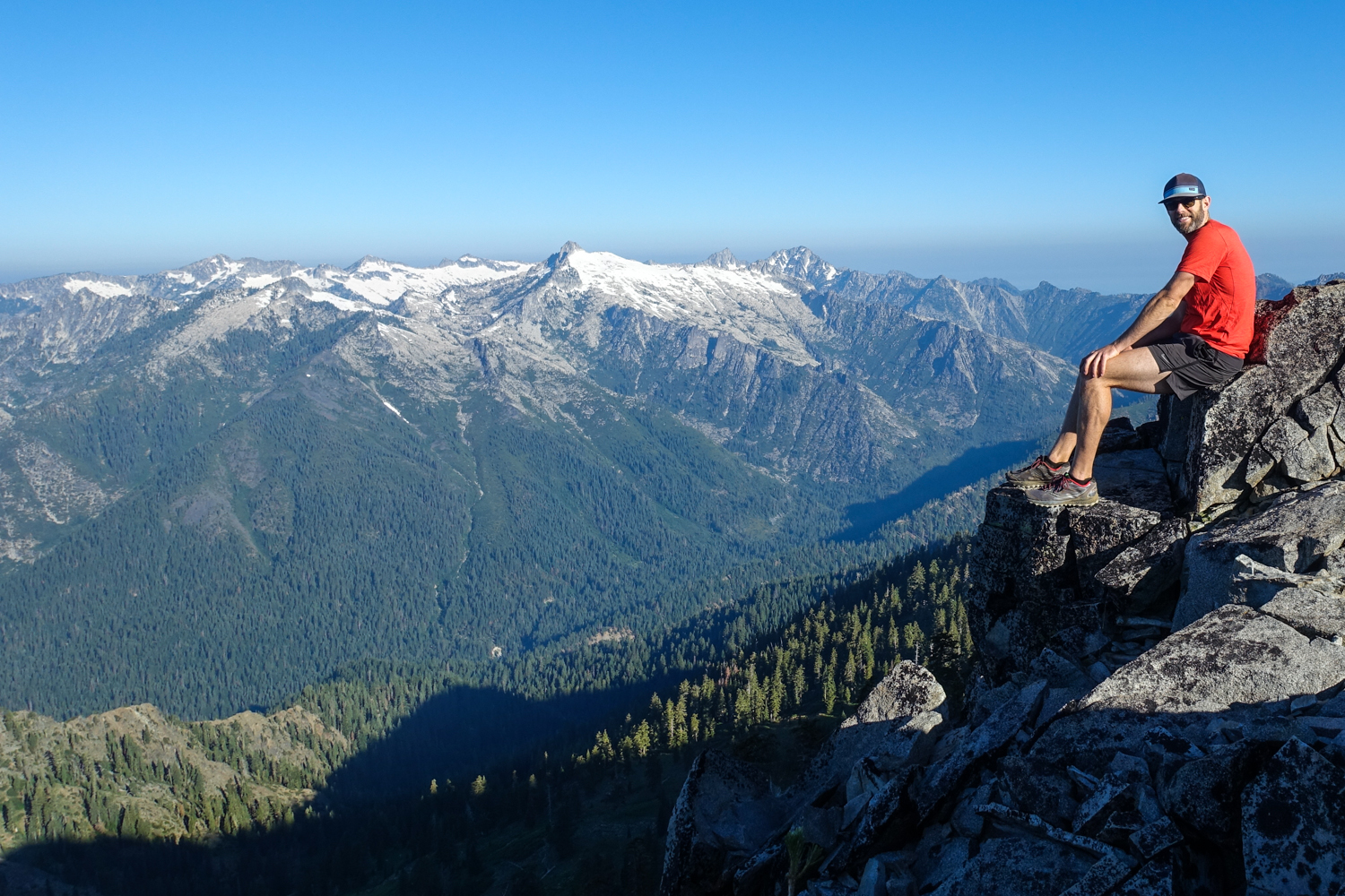backpacker perched on a rock overlooking the trinity alps in california