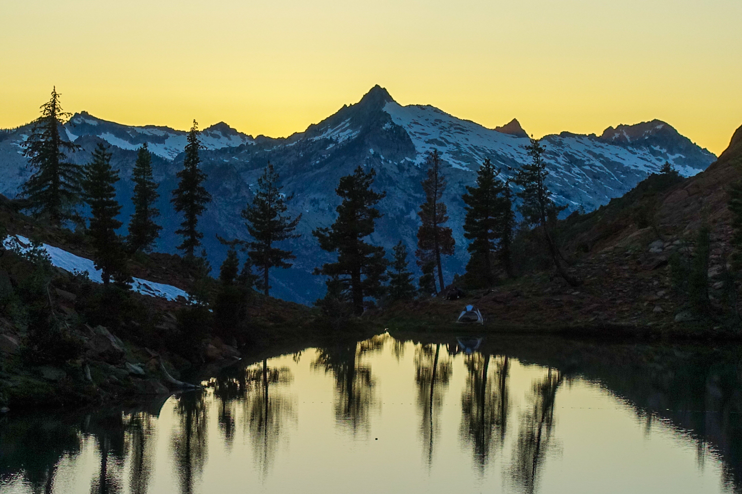 sunset over the trinity alps with an alpine lake reflecting the trees 