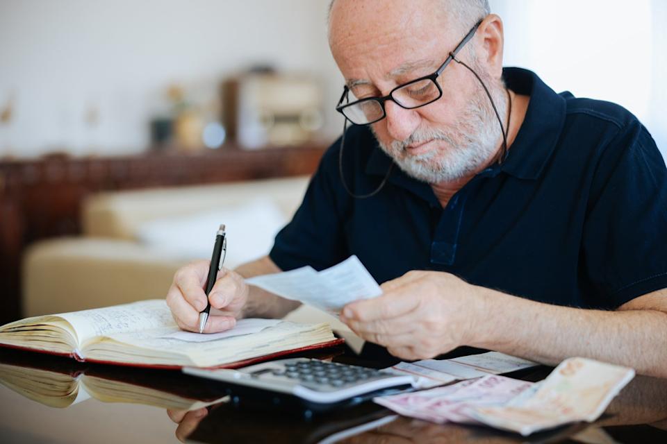 Person sitting at a desk with a calculator, writing in a notebook.