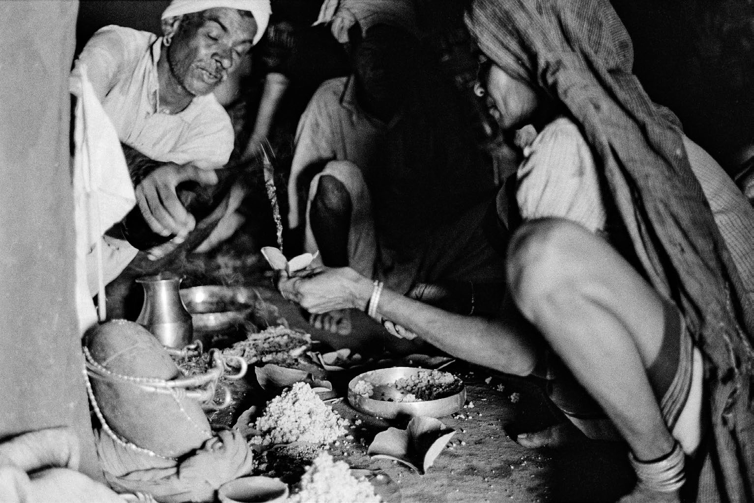 A black-and-white photograph of a group of men sitting on the ground