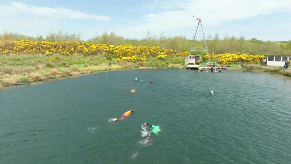 Neil swimming in a lake at North Devon Wake Park with 5 local swimmers all in wetsuits