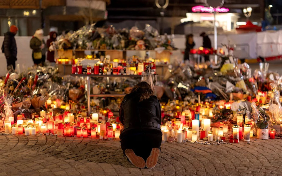 A woman lights a candle at a makeshift memorial outside the