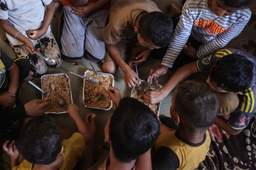 The children of Nihaya Al-Masri, a 35-year-old displaced Palestinian woman from Beit Hanoun, sharing a meal provided by a charity kitchen in Khan Yunis, in the southern Gaza Strip, October 6, 2026. — AFP pic