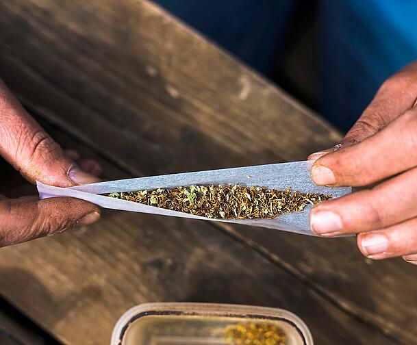 Vor einem Jahr hat es die Ampel legalisiert: Eine Person dreht Tabak und Cannabis in ein Zigarettenpapier. 365 Tage nach Inkrafttreten der neuen Regelungen zu Cannabis lässt sich eine erste Bilanz ziehen.