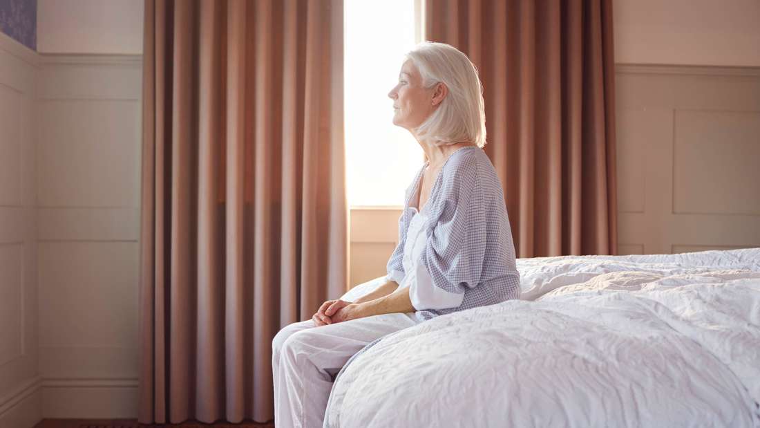 Frau sitzt traurig auf dem Bett