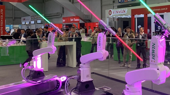 Besucher der Hannover Messe schauen sich an einem Messestand Roboter an. © NDR Foto: Marco Heuer