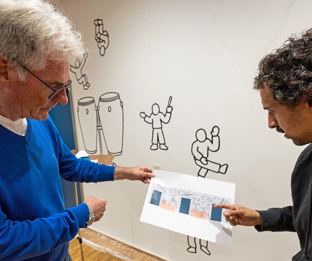 Thomas Wolf, der Vorsitzende der Jugendmusikschule, spricht mit Künstler Ben El Halawany über dessen Entwurf. Erste Figuren sind schon auf der 15 Meter langen Wand, die El Halawany gestalten wird.