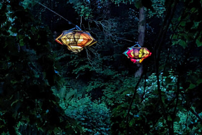„Color Floating“ in Zwönitz: Für die abends leuchtenden Objekte über dem Teich im etwas versteckten Austelpark hat die aus einer kurdisch-türkisch-iranischen Familie stammende Künstlerin Nevin Aladag verschiedenfarbige Strumpfhosen im Stile von Designlampen der 1960er-Jahre verwendet, die an die Textilproduktion und kulturelle Transformationen der Region erinnern.
