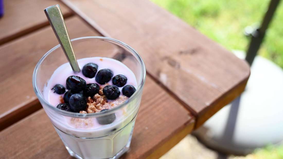 Naturjoghurt mit Beeren und etwas Müsli in einem Glas.
