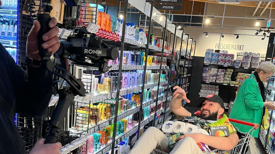 Der Rapper Daniel Kör liegt bei einem Musikvideodreh in einem Einkaufswagen voller Lebensmittel.