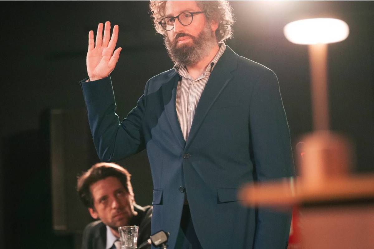 Mann steht bei The Jury Experience mit erhobener Hand im Gerichtssaal, links hinter ihm sieht man einen weiteren Mann sitzen.