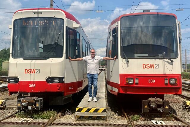 DSW-Betriebsleiter Ralf Habbes steht zwischen einer neuen Stadtbahn von HeiterBlick und einem alten B-Wagen, der noch umgebaut werden soll