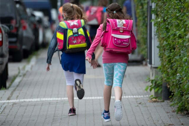 Schulkinder rennen über einen Gehweg