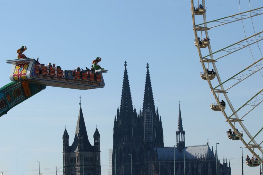 Fahrgeschäfte der Deutzer Kirmes sind vor dem Kölner Dom und Groß St. Martin zu sehen.