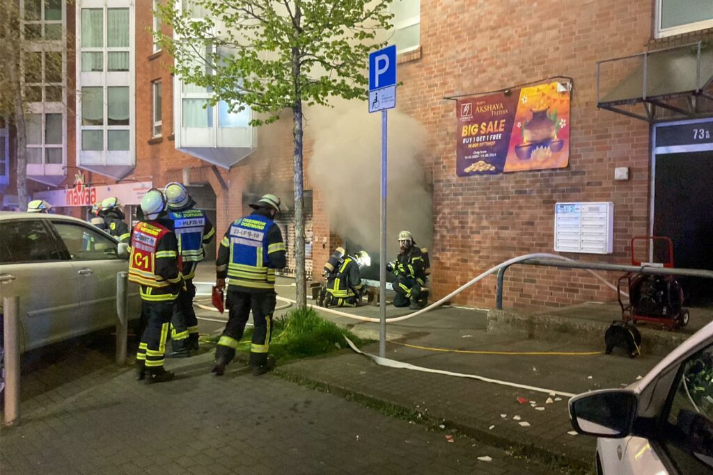 Einsatzkräfte der Feuerwehr versuchen in ein stark verrauchte Gebäude an der Rheinischen STraße in Dortmund einzudringen