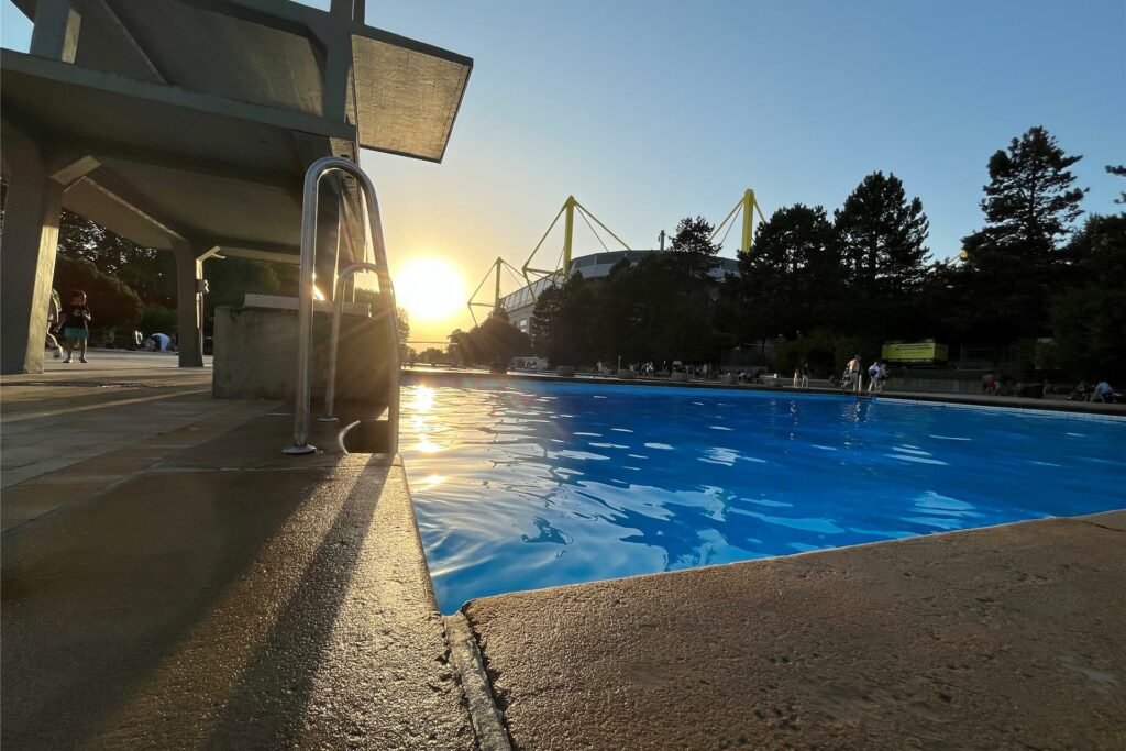 Die Sonne geht über dem Freibad Volkspark und dem Signal-Iduna-Park in Dortmund auf.