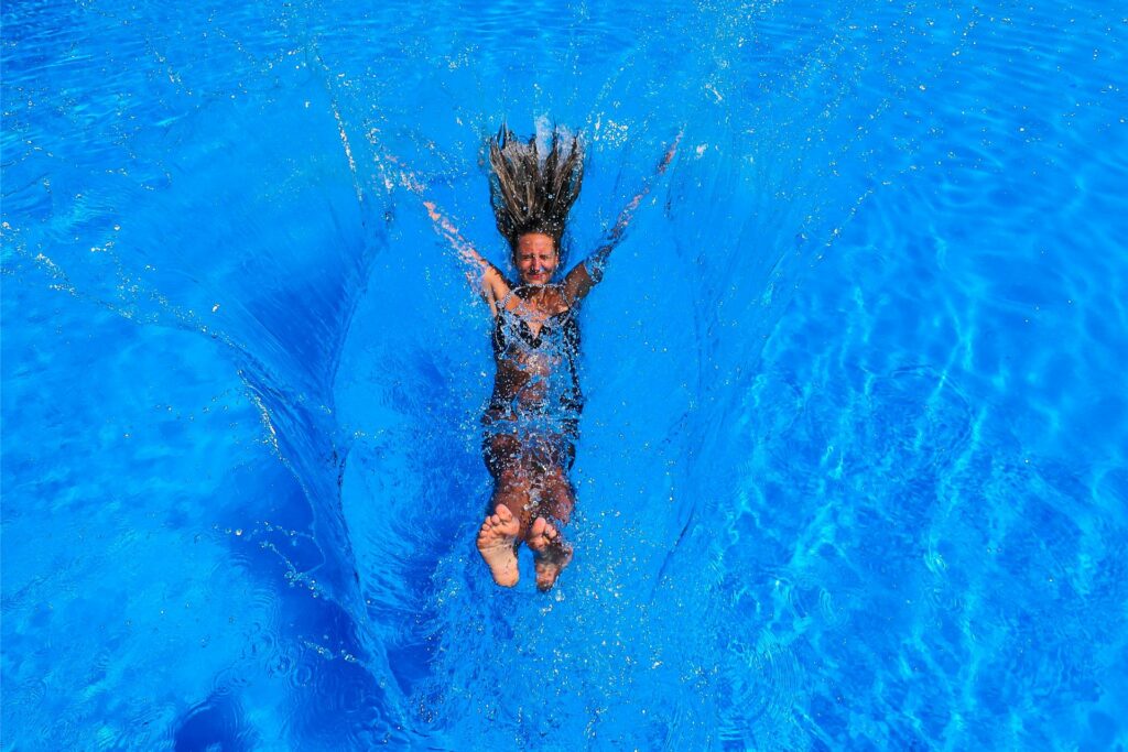 Eine Frau springt im Freibad in Dortmund Deusen in das Becken.