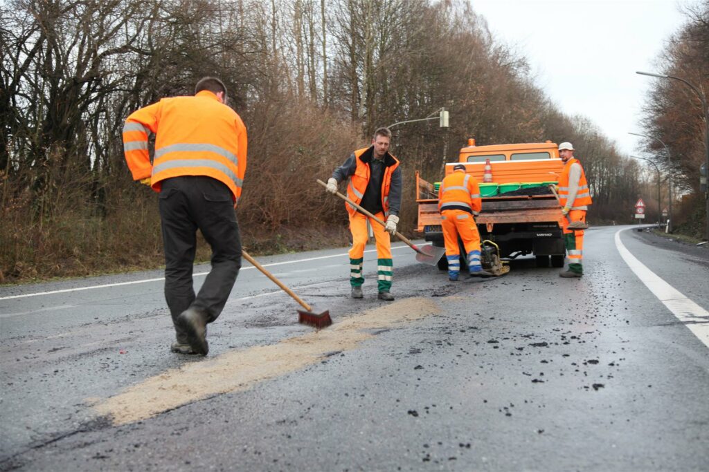 Arbeiter flicken auf einer Straße in Dortmund Schlaglöcher.
