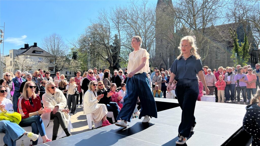 Models präsentieren aktuelle Outfits und Accessoires auf dem Laufsteg mitten auf dem Marktplatz.