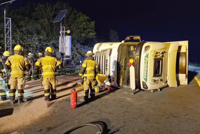 Ein spanischer Sattelzug liegt in der Tangente von der A2 auf die A1 im Kamener Kreuz auf der Seite. Mehrere Feuerwehrleute sind drumherum zu sehen.