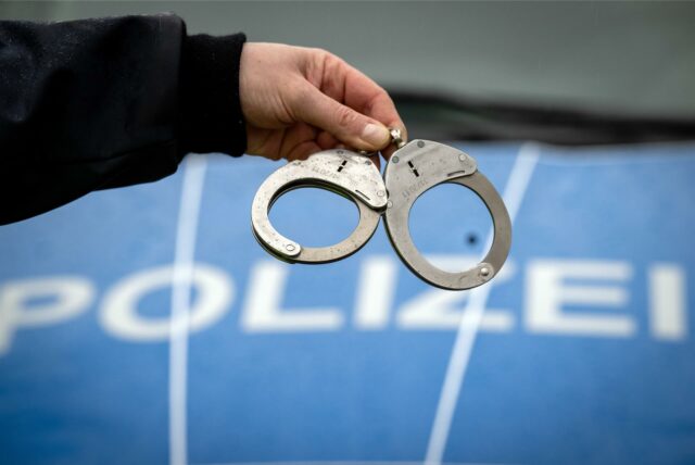 Ein Polizist hält ein Paar Handschellen.