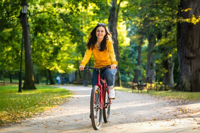 Symbolbild für Fahrradfahren in Dortmund. Eine Frau fährt in einem Park Fahrrad.